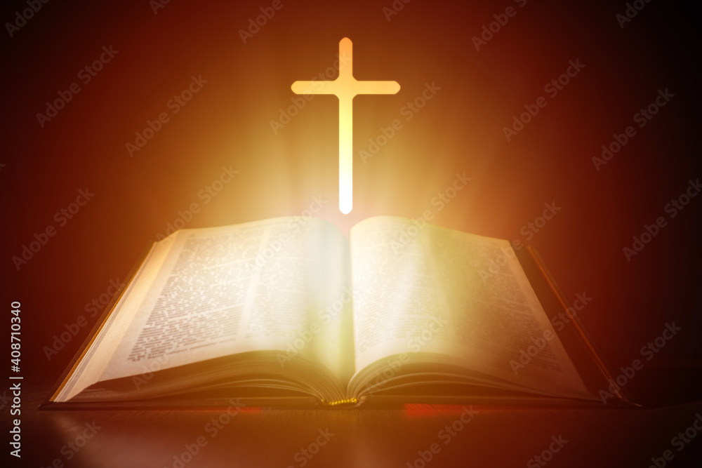 Bible and cross on a dark background. Bright light comes from Christian Bible. Cross next to the open book. Bible study concept. Studying Christian religion Reading religious literature.