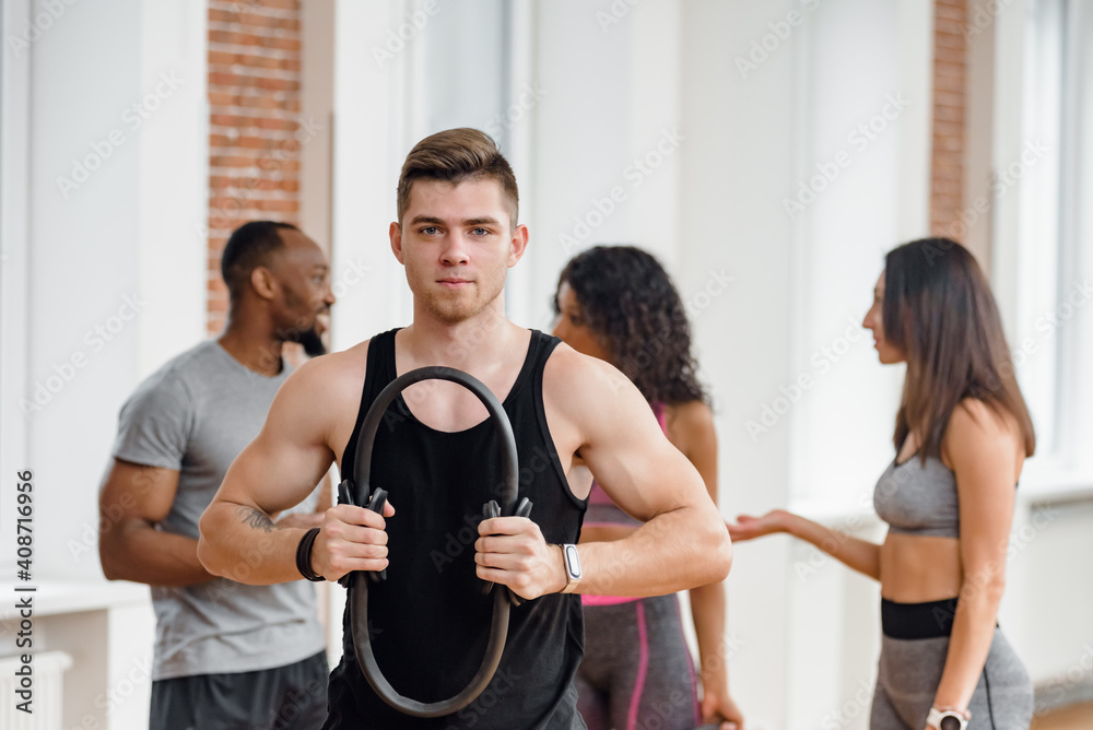 Young muscular man training with friends and doing exercise with resistance ring Young muscular man training with friends and doing exercise with resistance ring
