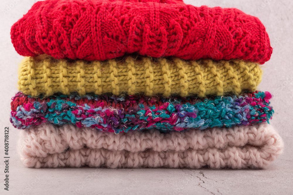 Winter knitted warm color sweaters folded in stack on table. Winter knitted warm color sweaters folded in stack on table.