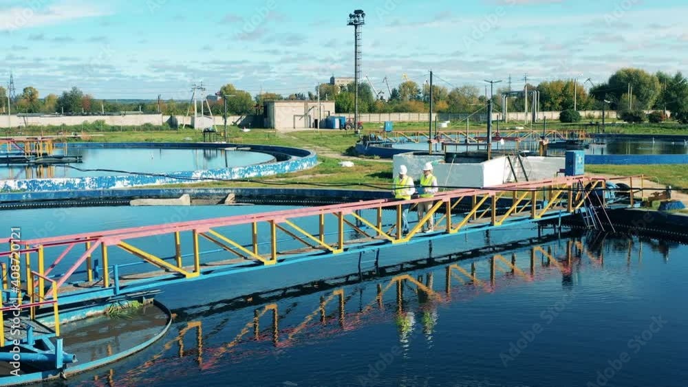 Male wastewater treatment operators inspecting a circular clarifier Male wastewater treatment operators inspecting a circular clarifier