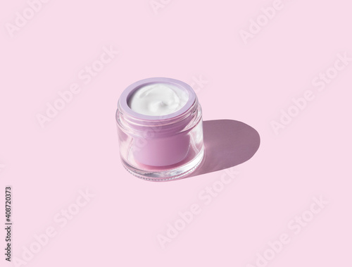 White antiaging face cream in pastel purple jar on pink background. Beauty skin care product
