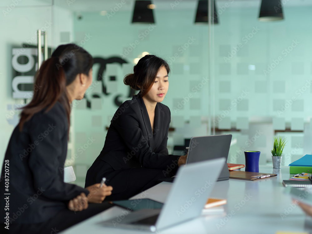 Two businesswomen working on their project in meeting room Two businesswomen working on their project in meeting room
