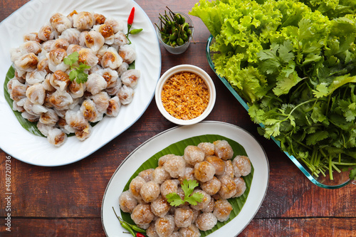 Steamed rice skin dumpling and tapioca ball filled with minced pork and peanut - Thai food called Khao krieb pak mor and Saku Sai moo on the wooden background