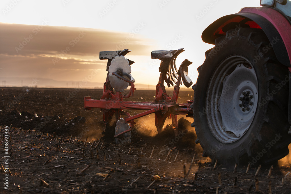 Obraz premium Tractor on the field during sunset.