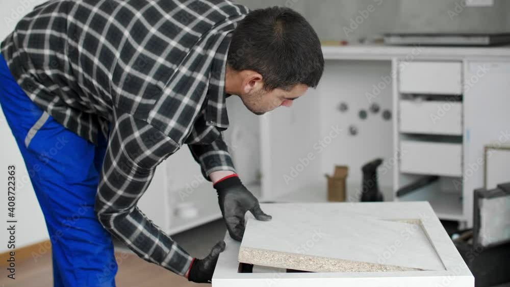 A carpenter with a corded jigsaw cutting a part of the wooden surface (board) A carpenter with a corded jigsaw cutting a part of the wooden surface (board)
