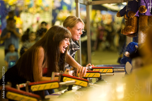 Two female friends playing a game at an amusement park photo