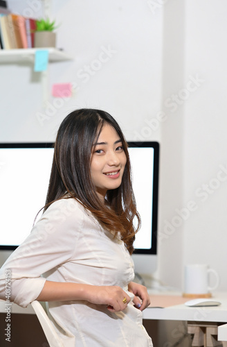 Portrait of casual young female in creative workplace and smiling to camera.