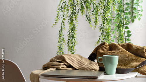 Obraz na plátně Laptop, mug, sweater and bag on the coffee table in Biophilia leisure corner