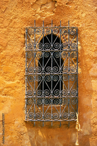 Ornate ironwork on arched window on stucco wall, Marrakesh, Morocco