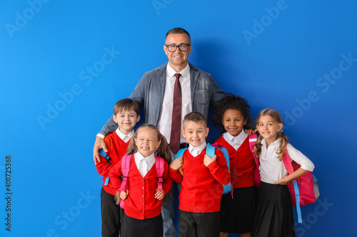Little pupils with teacher on color background