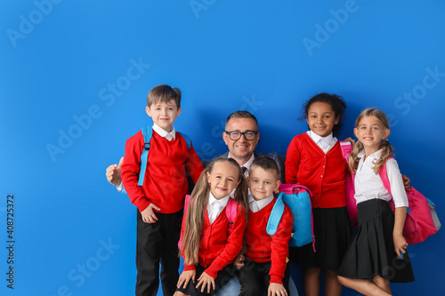Little pupils and teacher on color background