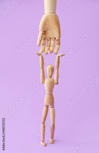 Wooden mannequin and hand on color background photo