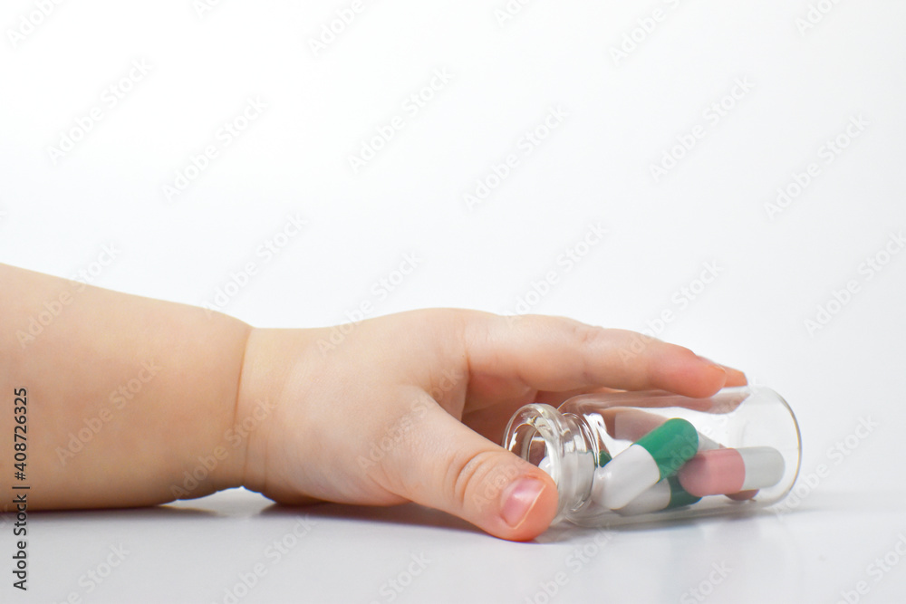 A child's hand reaches for a tube of capsules. Danger of medicament intoxication A child's hand reaches for a tube of capsules. Danger of medicament intoxication