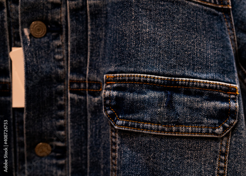 Selective focus on denim jean jacket pocket in clothes shop. Denim jacket pocket texture background. Textile industry. Jeans fashion and shopping concept. Clothing concept. Denim jacket for sale. © Artinun