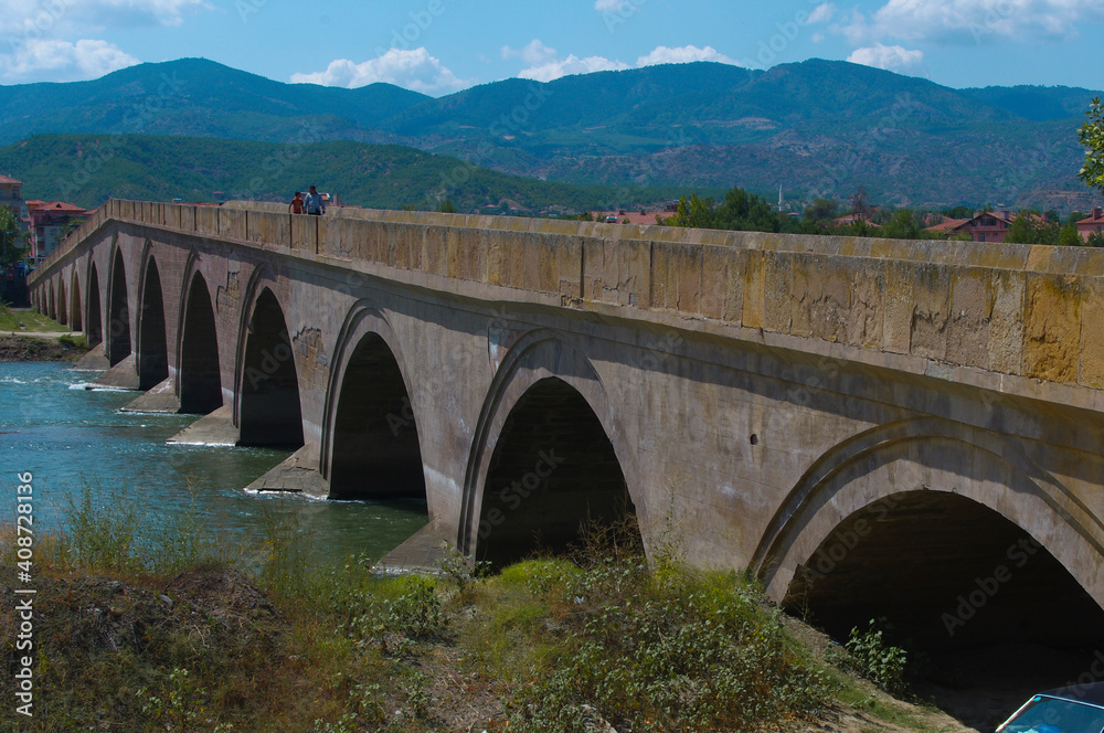 Historical Ottoman stone bridge and Kızılırmak. River and bridge view. Rural settlement and arched structure. 