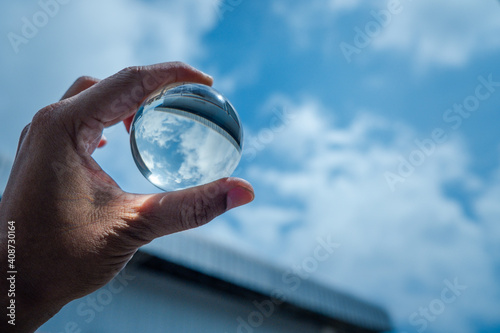The hand was holding a glass ball and shone at the blue sky.