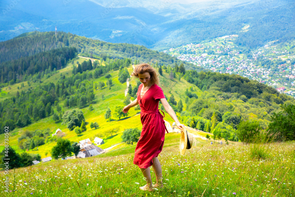 Beautiful girl the mountains. Woman in linen dress and straw hat travelling. Amazing summer nature around. Harmony and wanderlust concept. Rustic natural style. Wind blowing for dynamic photo.