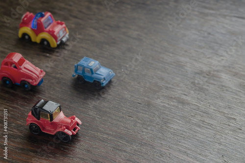 Children's imaginary concept games. Little Toy Cars racing headlong across a brown wooden surface.