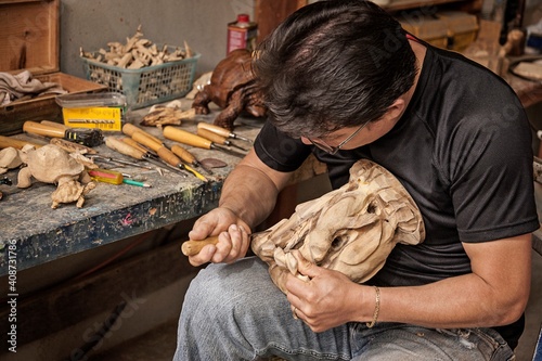 Ecuador, Galapagos Islands, Man using wood carving tool to create wood carving sculpture of 1 from Ecuador, Galapagos Islands,