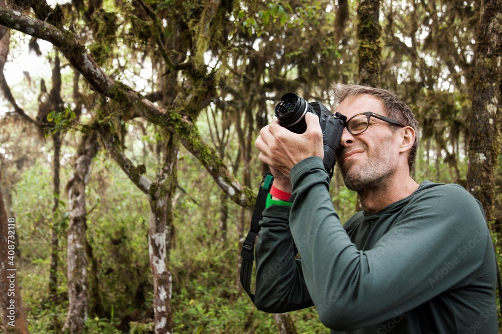 Ecuador, Galapagos Islands, Man taking pictures with digital camera on hike in jungle Ecuador, Galapagos Islands, Man taking pictures with digital camera on hike in jungle