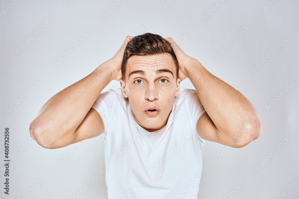 Nice man in a white t-shirt gestures with his hands emotions surprise studio Nice man in a white t-shirt gestures with his hands emotions surprise studio