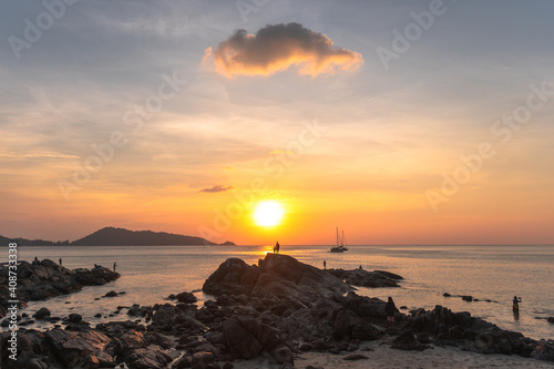 Golden sky behind the mountain, father and son stand atop a rock to watch the sunset at Kalim Beach, .next to Patong Beach, Phuket.