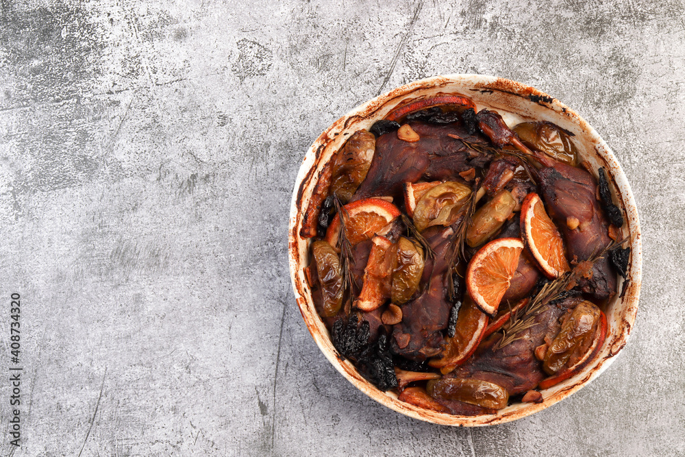 Roasted duck legs in a white baking dish on a dark background. Top view, flat lay Roasted duck legs in a white baking dish on a dark background. Top view, flat lay