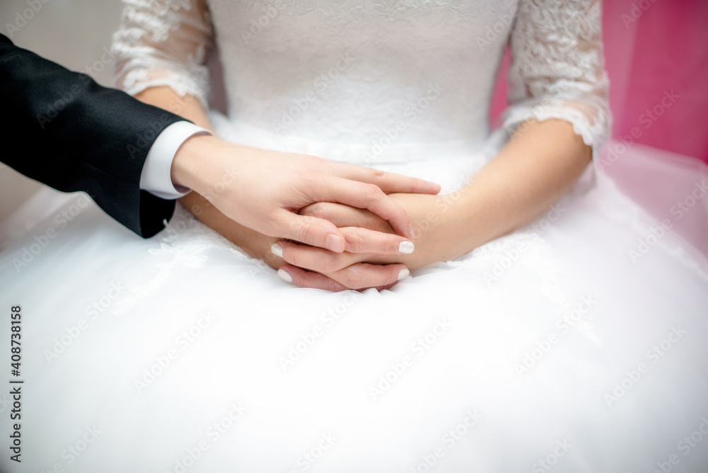The groom holds the hand of the bride in a white dress
