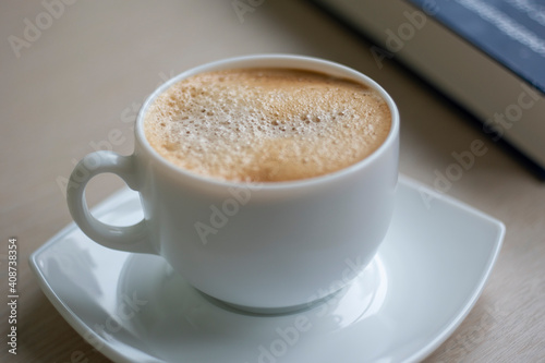 Cup of Morning cappuccino coffee with milk and blue book photography