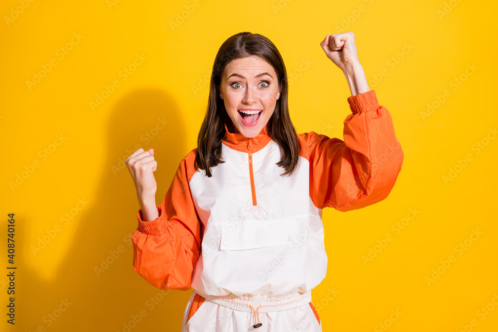 Photo of victorious brunette woman raise fists scream win match isolated on vivid shine yellow color background Photo of victorious brunette woman raise fists scream win match isolated on vivid shine yellow color background