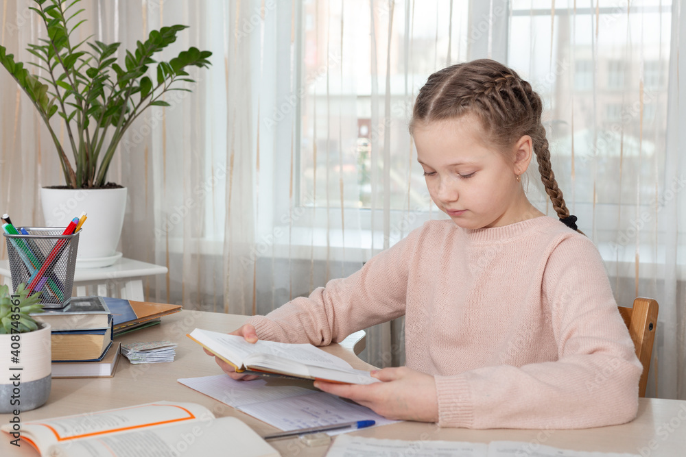 Schoolgirl sitting at desk and reading book. Education Back to school - Image Schoolgirl sitting at desk and reading book. Education Back to school - Image