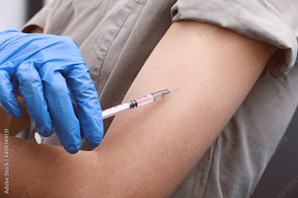 Female doctor or nurse giving shot or vaccine to a patient's shoulder. Vaccination and prevention against flu or virus pandemic. Female doctor or nurse giving shot or vaccine to a patient's shoulder. Vaccination and prevention against flu or virus pandemic.