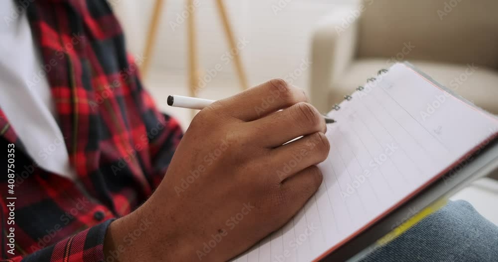 Hand of man writing to do list in notepad at home
