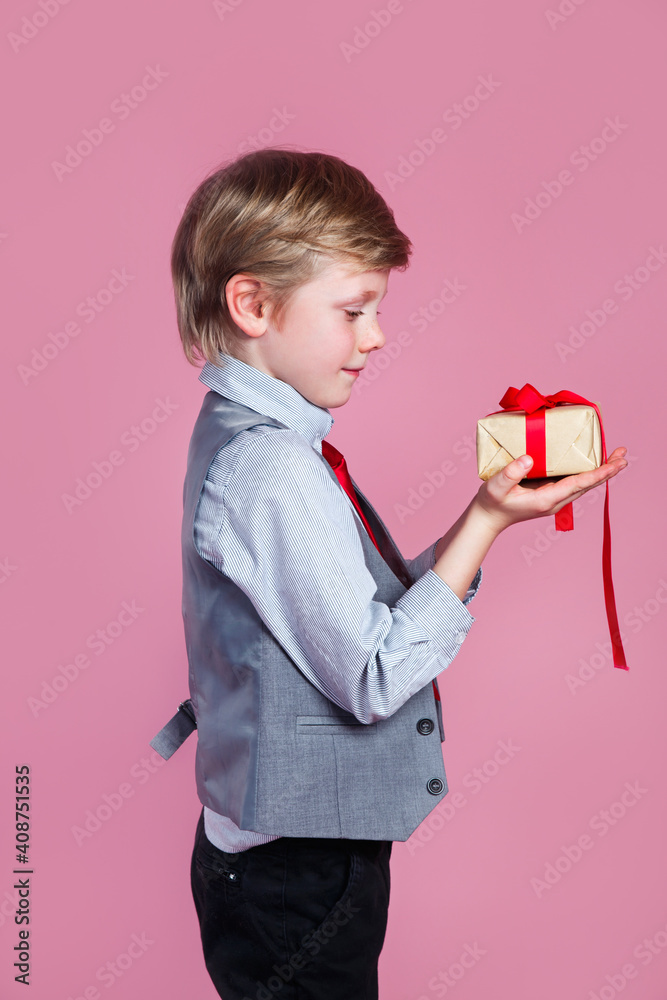 Valentines day. Charming little boy with gift box on pink studio background Valentines day. Charming little boy with gift box on pink studio background