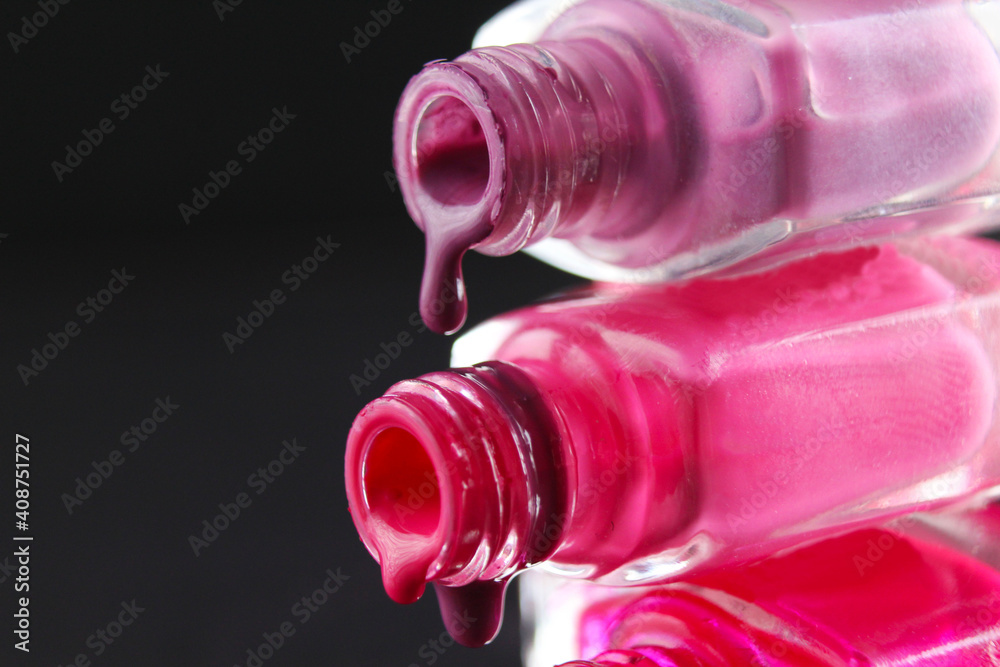 drops of red bearded pink nail polish flow from the bottle of the bottle on a black dark background with a copyspace drops of red bearded pink nail polish flow from the bottle of the bottle on a black dark background with a copyspace