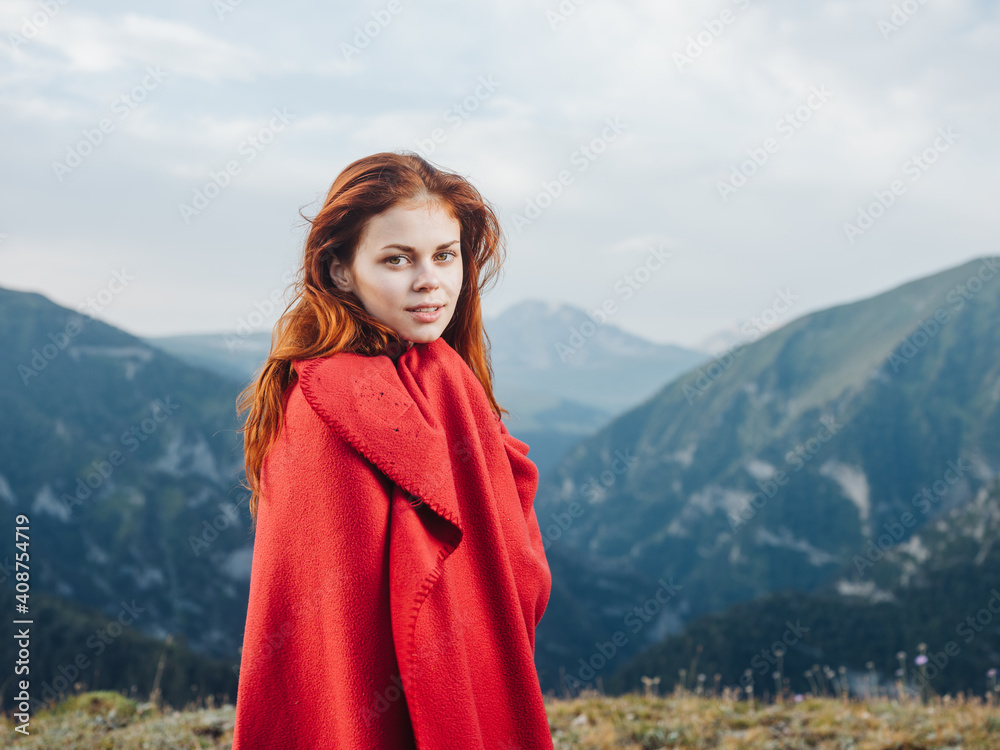 Red-haired woman with a plaid on her shoulders in the mountains on nature travel tourism