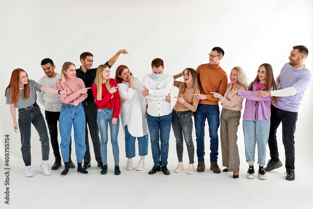 people bully a sick infected person standing in the center in medical mask, men and women poke a finger at him and laugh. coronavirus, covid-19 concept people bully a sick infected person standing in the center in medical mask, men and women poke a finger at him and laugh. coronavirus, covid-19 concept