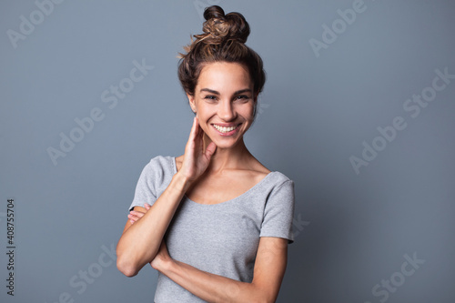 Beautiful authentic joyful woman with bun hair and natural smile on a gray background
