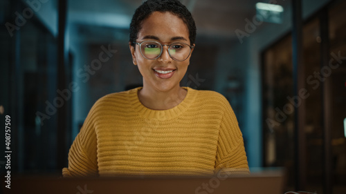 Close Up Portrait of Young Hispanic Marketing Specialist Working on Laptop Computer in Busy Creative Office Environment. Beautiful Diverse Multiethnic Female Project Manager is Browsing Internet. photo