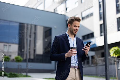 Handsome businessman using smartphone and smiling. Happy young man using mobile phone apps, texting message, browsing internet, looking at smartphone. Young people working with mobile devices.