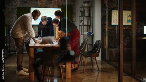 Diverse Multiethnic Team are Having a Conversation in a Meeting Room Behind Glass Walls in a Creative Office. Colleagues Lean On a Conference Table and Discuss Business  App User Interface and Design.
