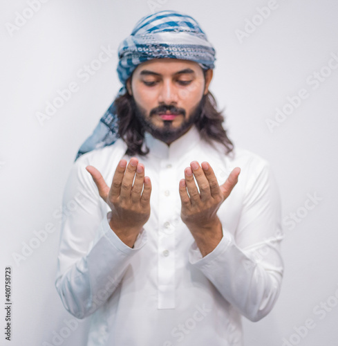 Religious muslim man praying on grey background photo