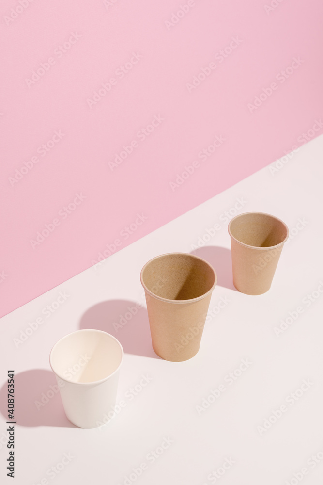 Trending colors. Design of paper cups on white table on pink background. Ecology, environmental pollution by plastic, waste recycling concept. Copy space Trending colors. Design of paper cups on white table on pink background. Ecology, environmental pollution by plastic, waste recycling concept. Copy space