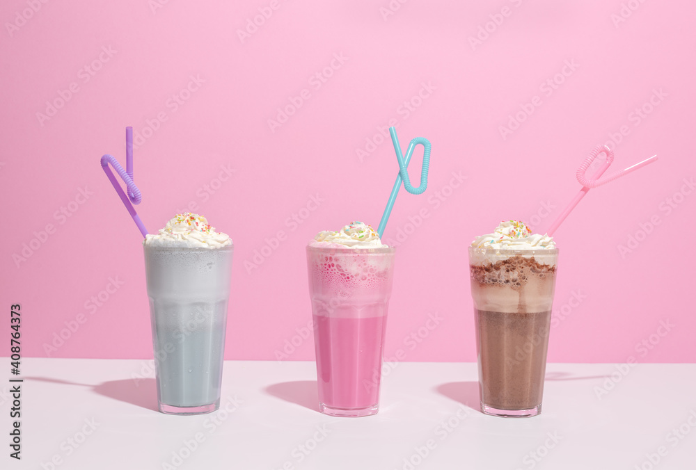 Strawberry, chocolate and vanilla milkshake with whipped cream on pink background. Place for text. Sweet drinks Strawberry, chocolate and vanilla milkshake with whipped cream on pink background. Place for text. Sweet drinks
