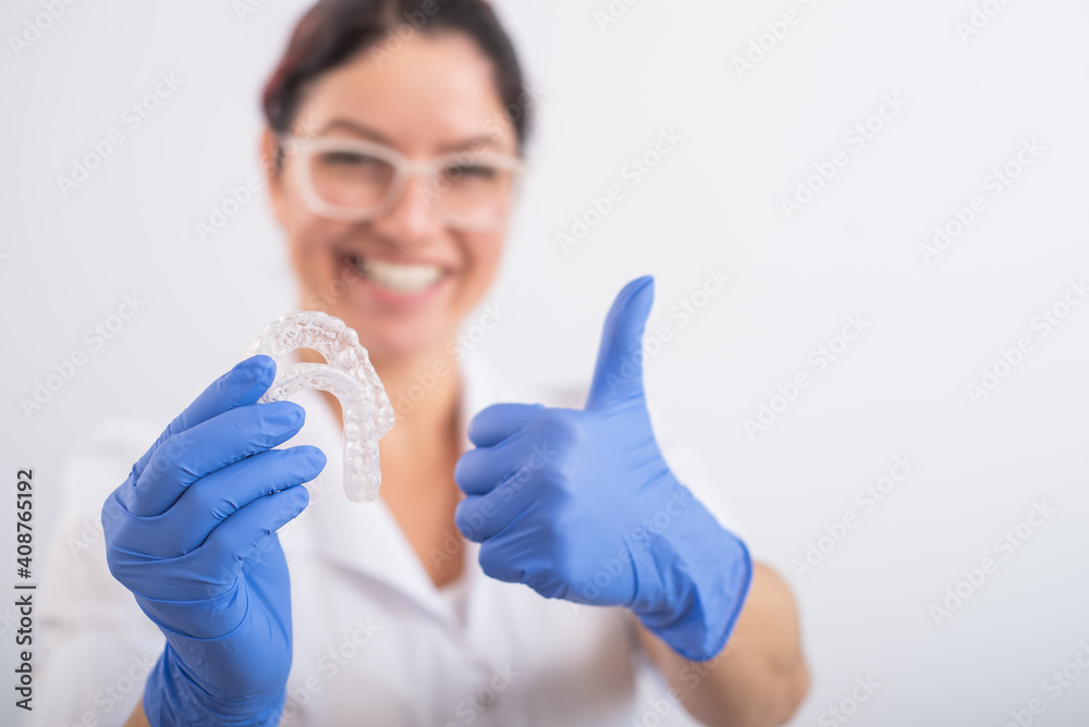 The orthodontist holds the removable transparent retainers The orthodontist holds the removable transparent retainers