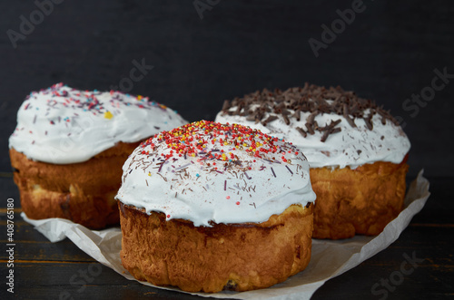 Ukrainian Easter bread or cake with white glaze decorated with multicolored rainbow sprinkle on the black wooden background