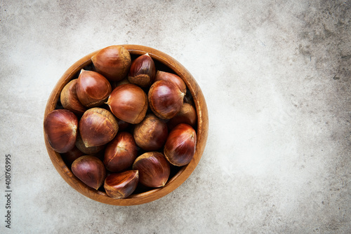 Obraz na płótnie Pile of fresh sweet chestnuts in a bamboo bowl over grey background
