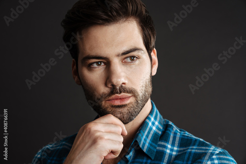 Confident handsome unshaven guy posing and looking aside