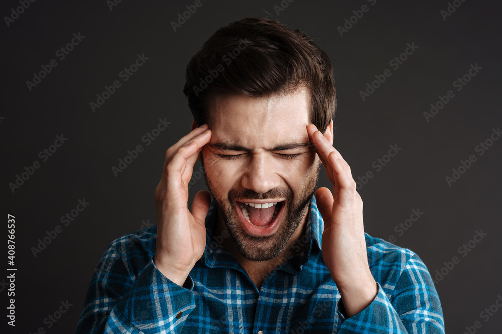 Unhappy handsome guy with headache screaming and rubbing his temples Unhappy handsome guy with headache screaming and rubbing his temples