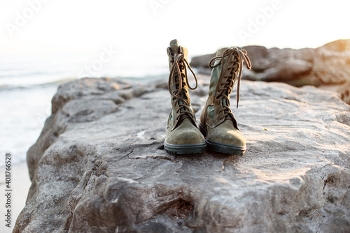 Army military boots with laces for men stand on the background of the sea and stone in sunny weather